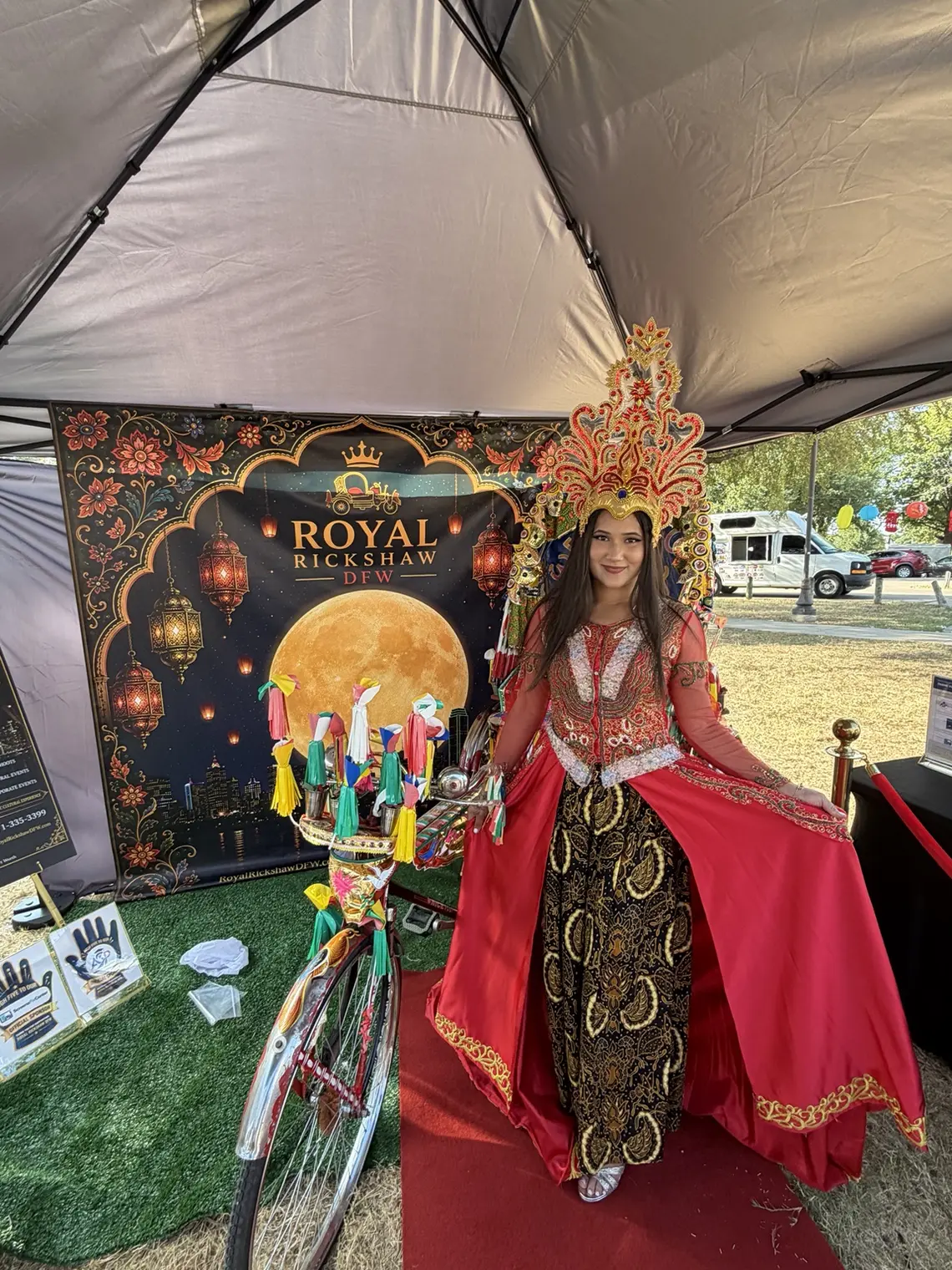 Performer in red traditional clothing beside the Royal Rickshaw