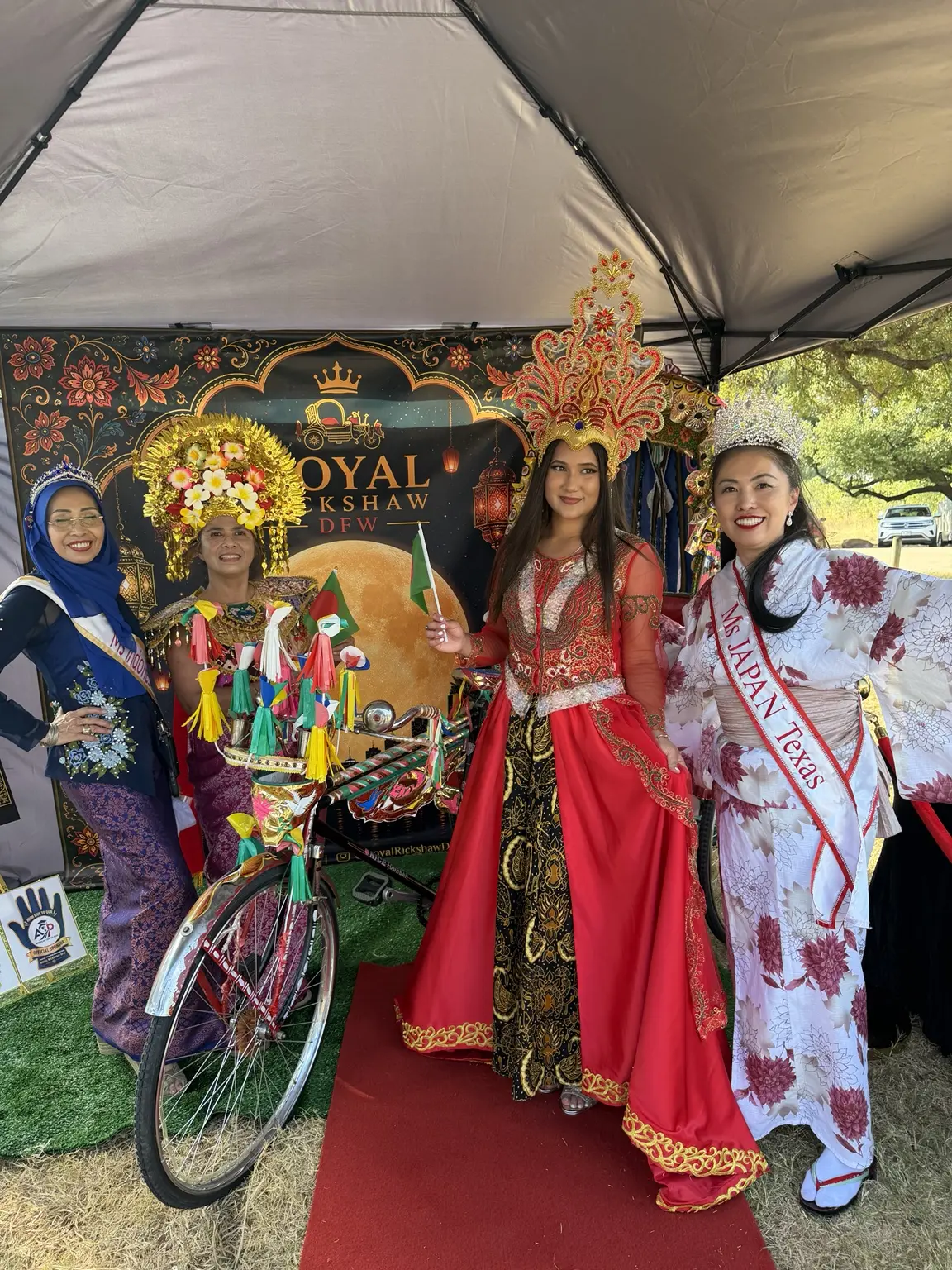 Three festival performers gathered around the Royal Rickshaw DFW display