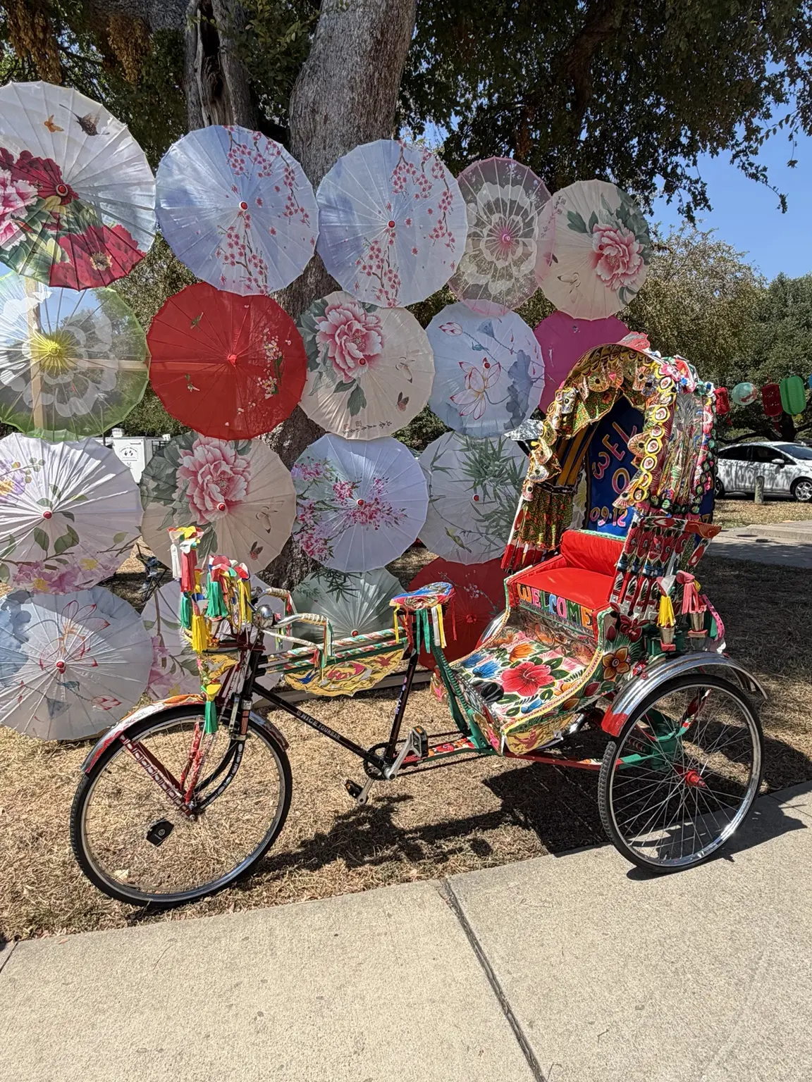 Full side view of the decorated rickshaw beside the Dallas Moon Festival umbrella display