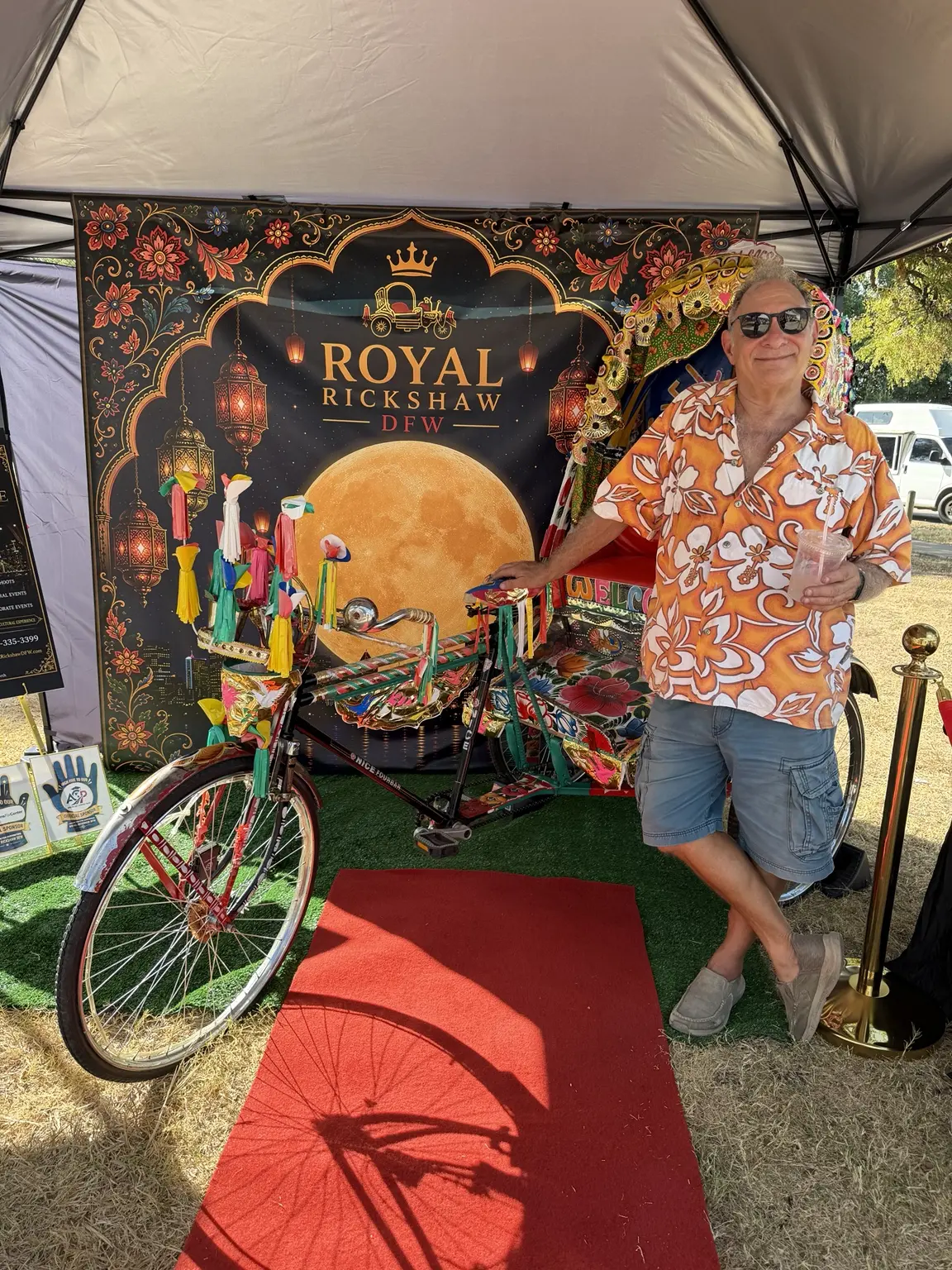 Festival visitor posing beside the colorful Royal Rickshaw DFW bicycle
