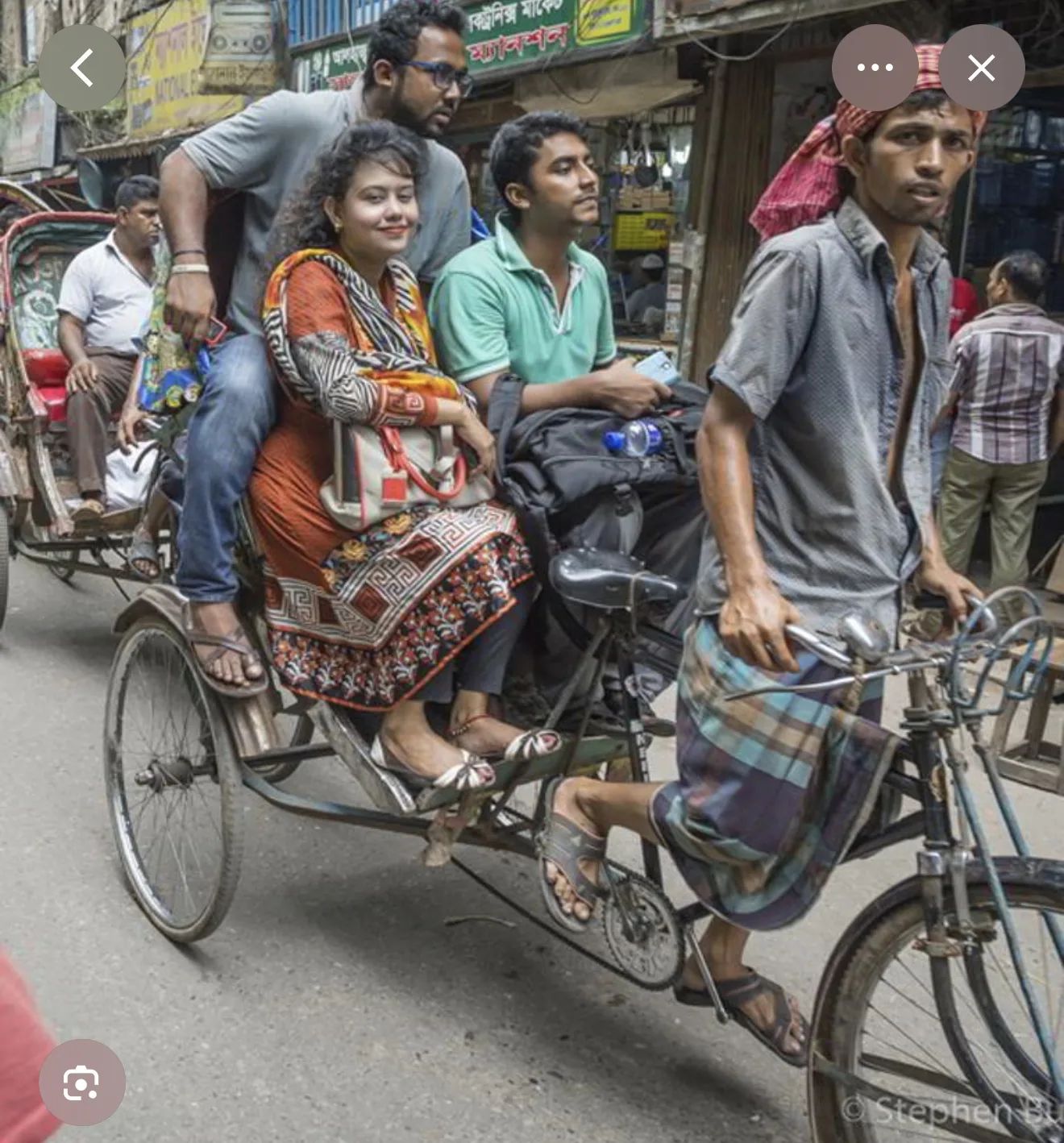 Reference image showing passengers in a rickshaw on a busy Bangladesh street