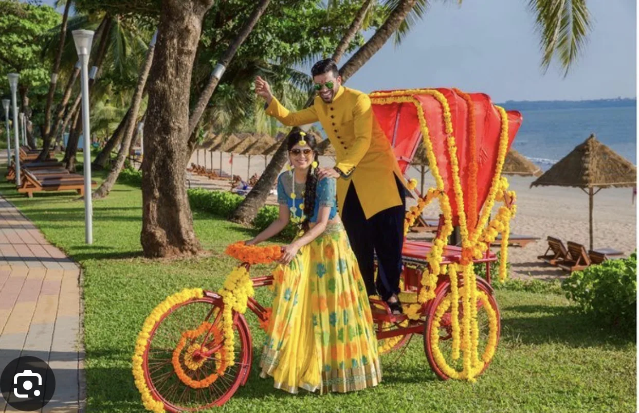Reference image of a couple posing with a decorated rickshaw at an outdoor celebration